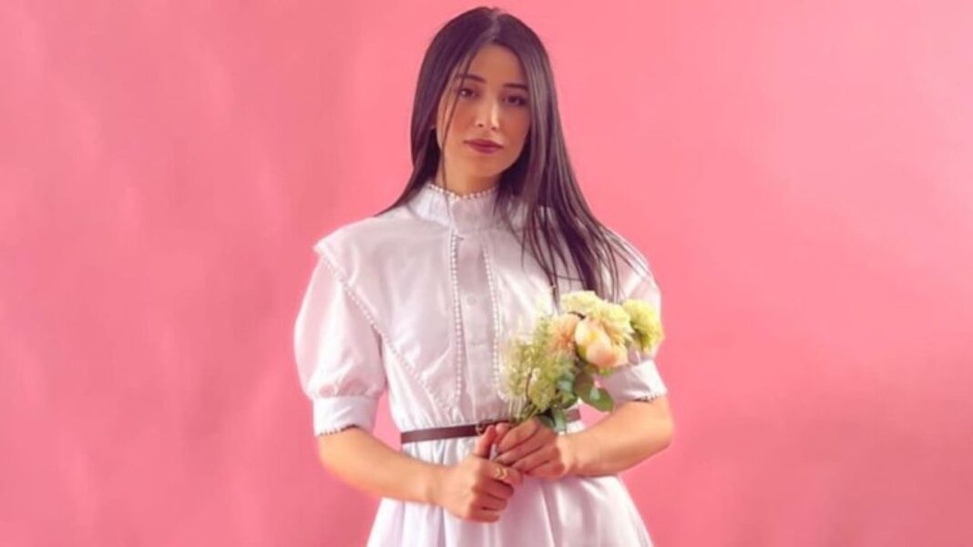 Mari algérien ou étranger ? Nahla TV fait son choix Femme avec bouquet de fleurs, portrait sur fond rose.