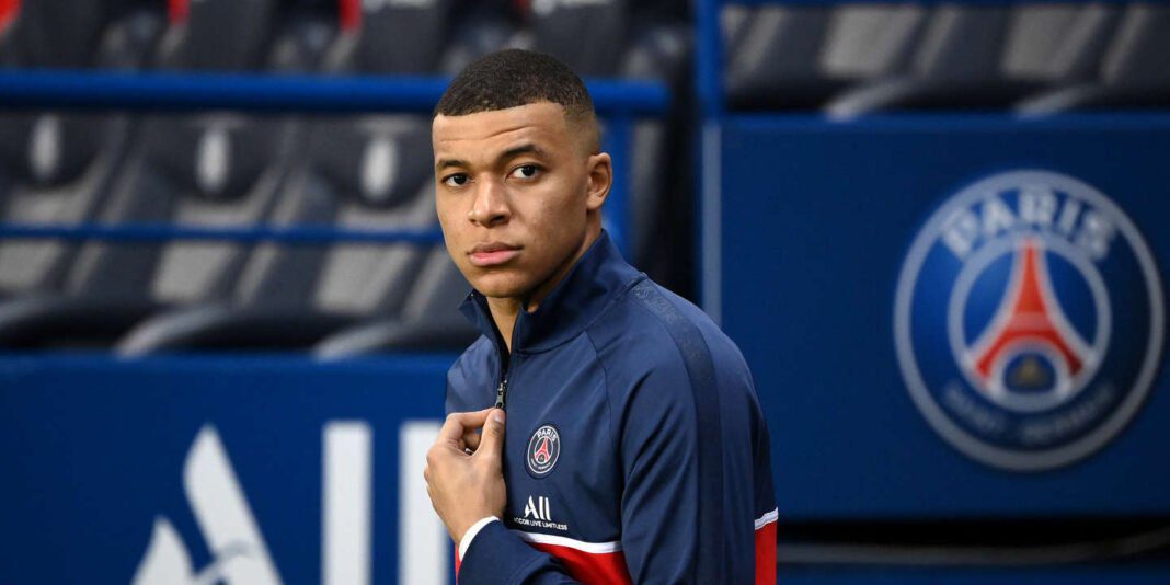 Kylian Mbappé en tenue du PSG dans un stade vide.