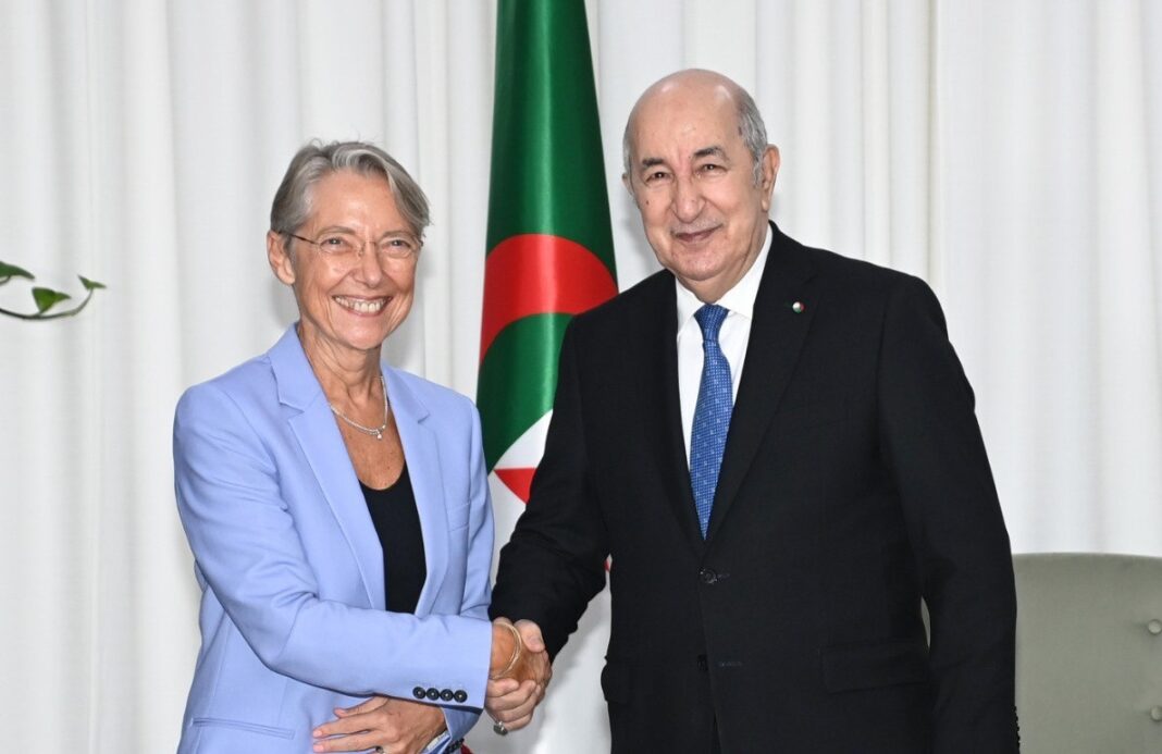 Deux dirigeants se serrent la main devant le drapeau algérien.
