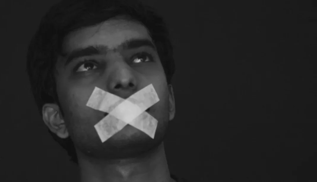 Jeune homme avec bouche bâillonnée Jeune homme avec bouche recouverte de ruban adhésif noir.