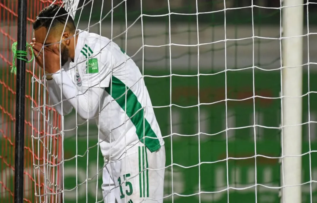 Footballeur algérien triste derrière la cage de but.