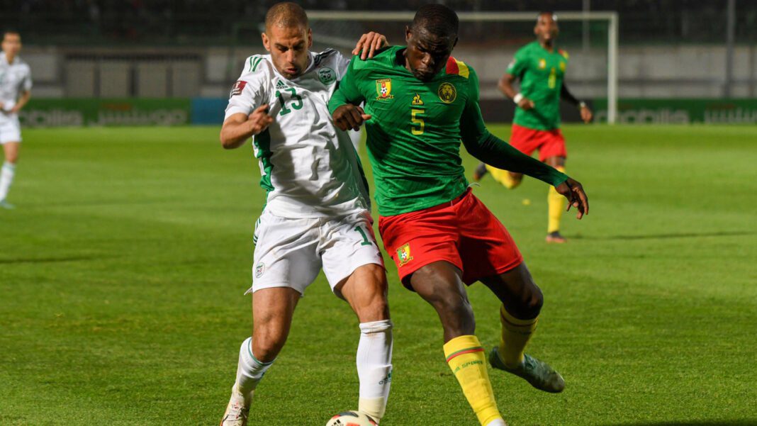 Joueur algérien et camerounais en duel lors d'un match de football.