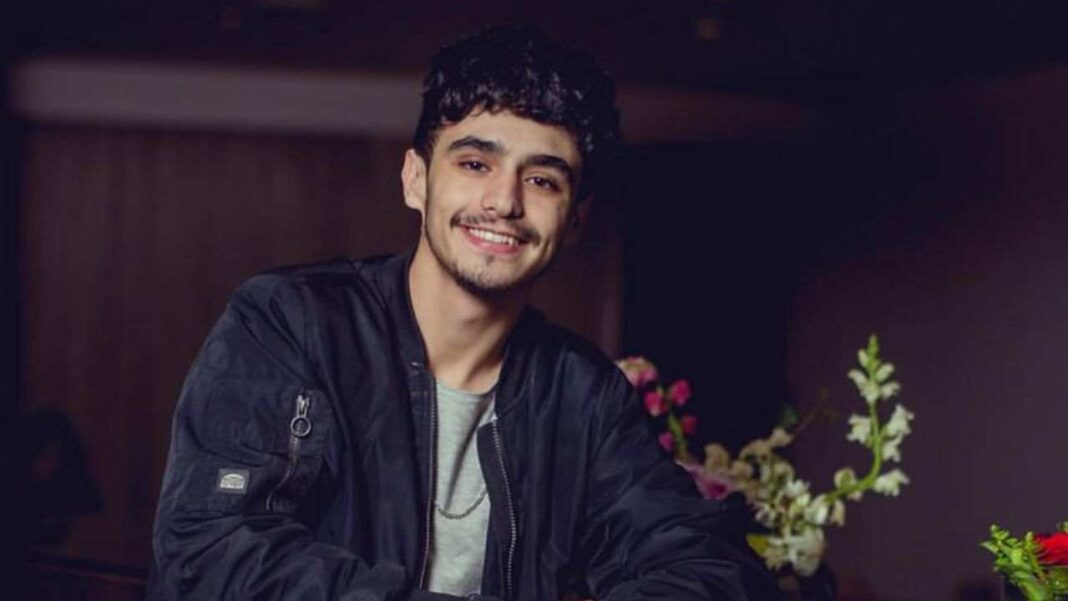 Algérie : Découvrez l’annonce surprenante de Stanley Jeune homme souriant portant une veste noire dans un environnement intérieur.