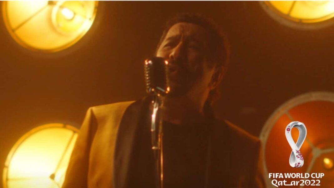 Découvrez l’hymne officiel de l’Algérien Cheb Khaled pour la coupe du monde 2022. Cheb Khaled chantant lors de la Coupe du Monde 2022, scène en studio avec éclairage chaud.