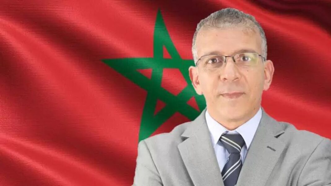 Hafid Derradji, commentateur sportif, devant le drapeau marocain.
