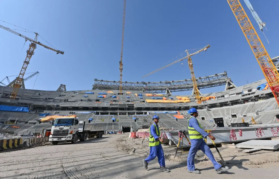 Travailleurs sur le chantier du stade au Qatar sous un ciel clair.