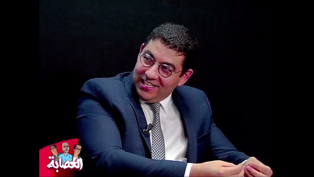 Jeune homme souriant en costume lors d'une interview ou discussion.