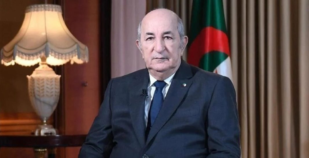 Homme politique algérien en portrait officiel Homme politique algérien en costume dans un cadre officiel avec drapeau algérien.