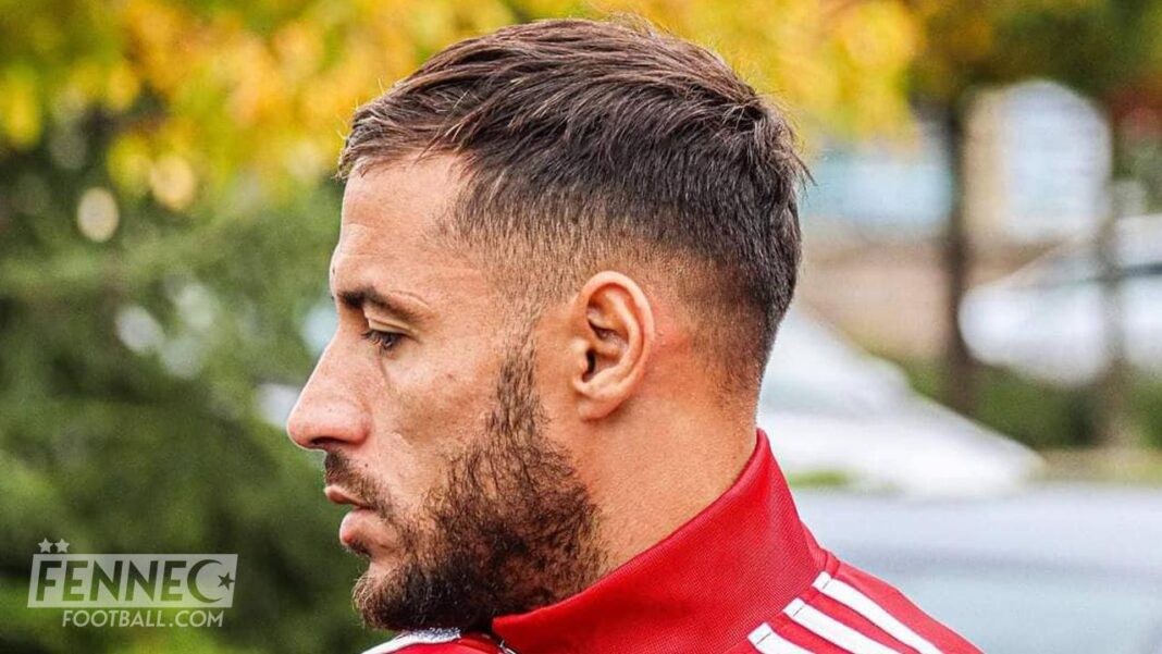 Youcef Belaili en profil, portant un maillot rouge, lors d'une séance d'entraînement.