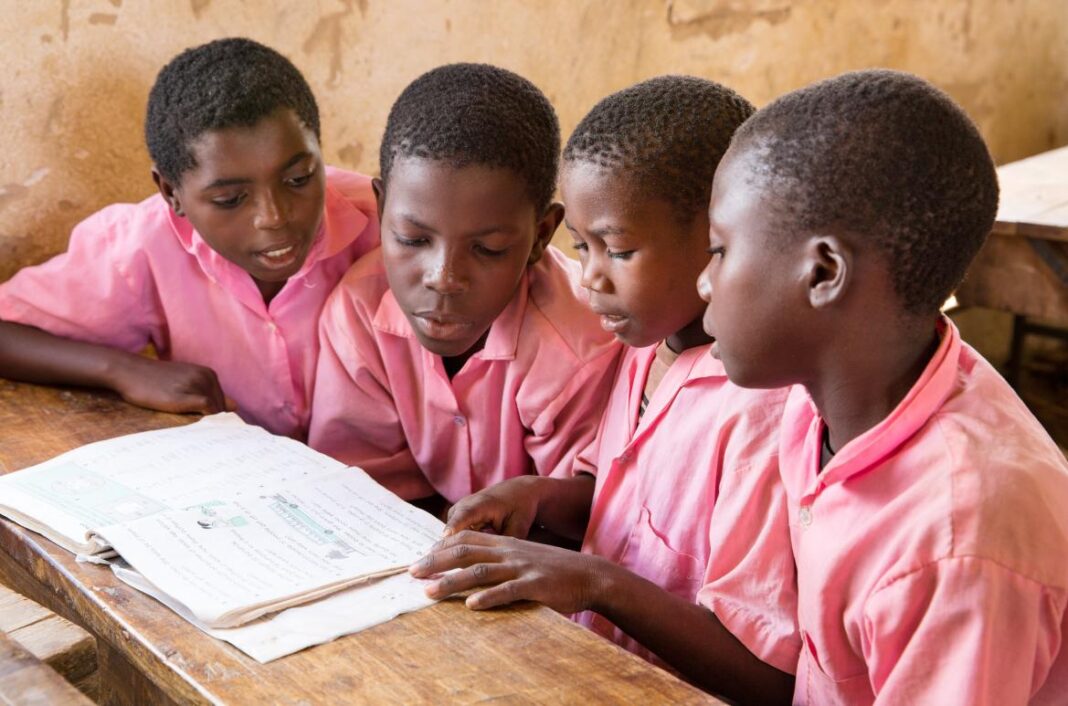 Jeunes élèves en classe au Nigéria, étudiant un livre scolaire.