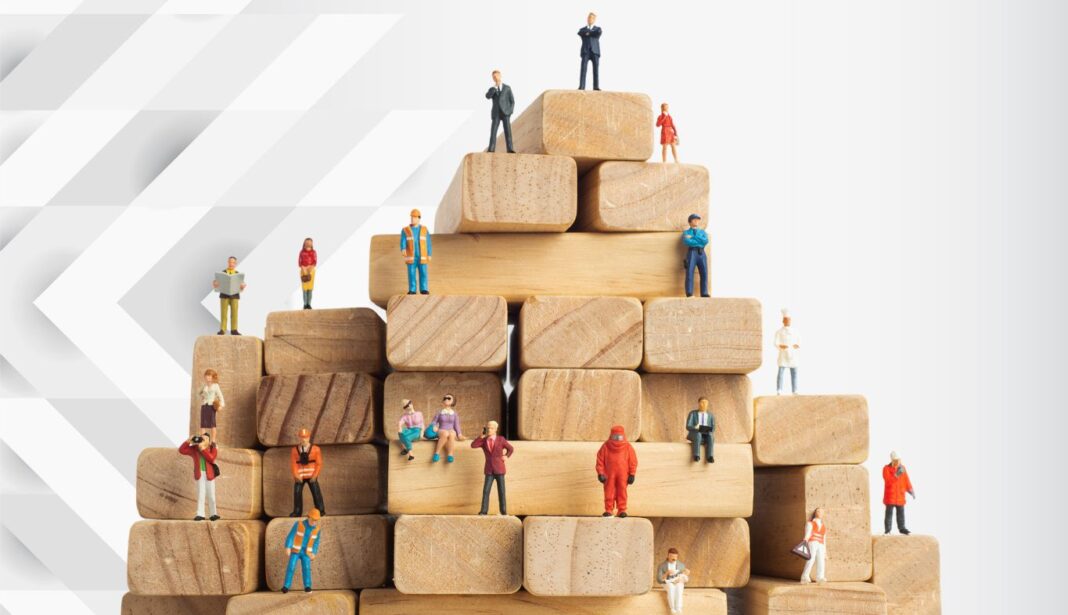 L’immigration, la solution contre la pénurie de main-d’œuvre dans les pays développés Figurines miniatures sur blocs en bois symbolisant la collaboration et la croissance.