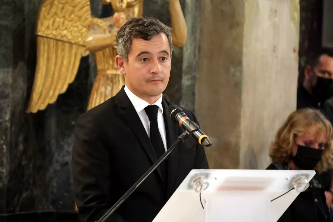 Homme en costume noir parlant à un micro lors d'une cérémonie officielle.