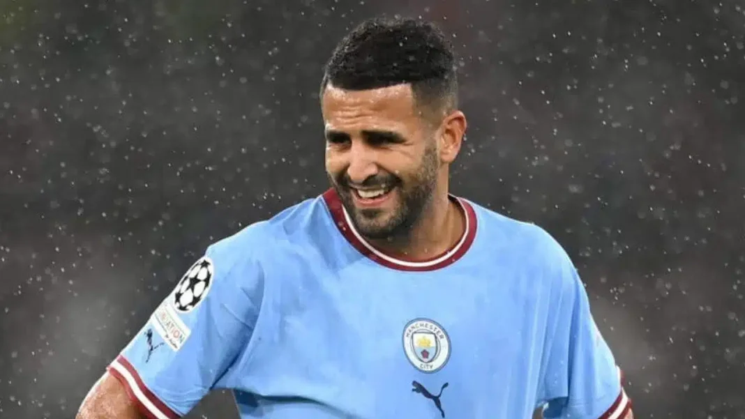 Riyad Mahrez avec un sourire Riyad Mahrez souriant en tenue de football sous la pluie.