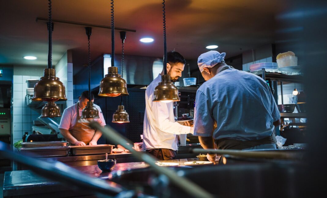Cuisiniers en cuisine professionnelle préparant des plats.