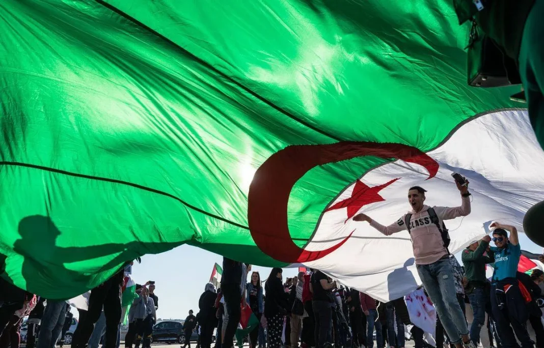Manifestation en Algérie avec drapeau national Groupe de manifestants tenant un grand drapeau algérien lors d'une manifestation.