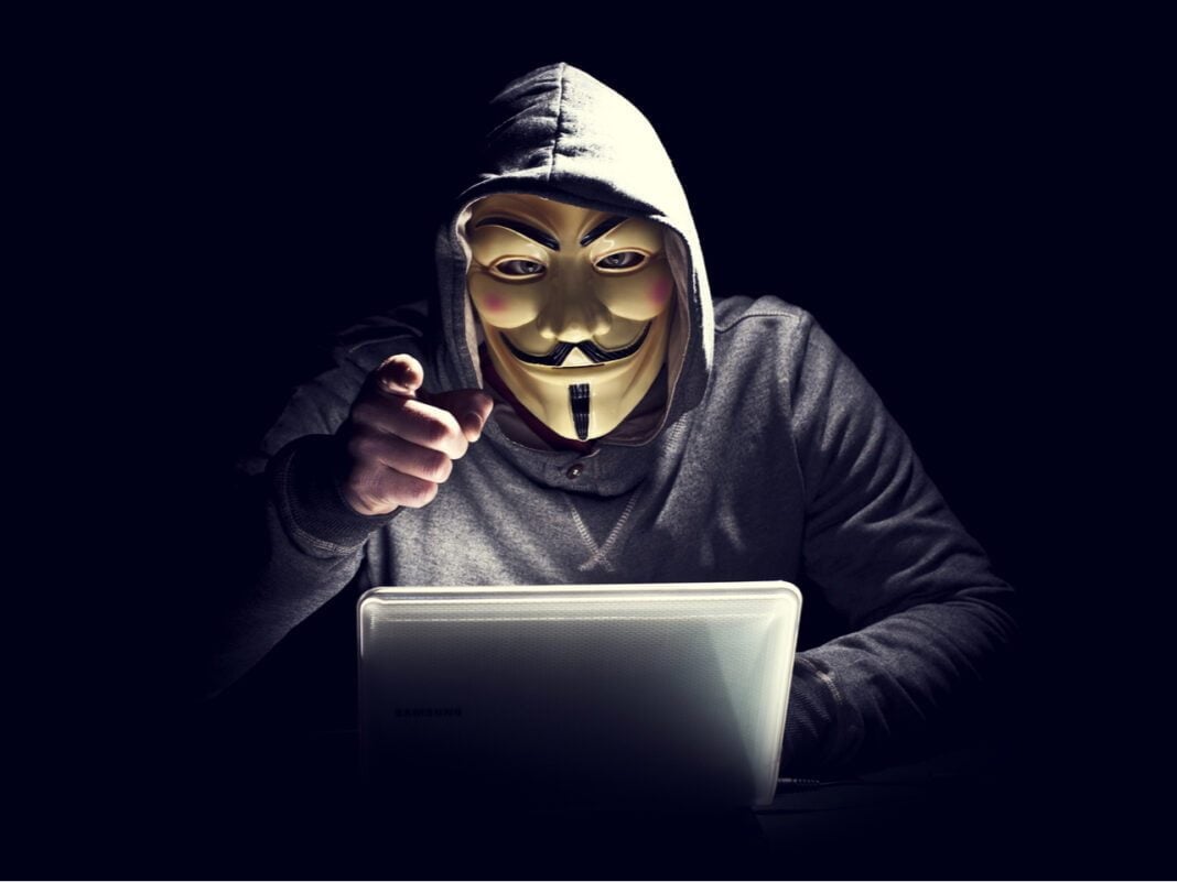 France : un hacker algérien condamné à… Hacker masqué portant un hoodie, pointant du doigt vers l'objectif.