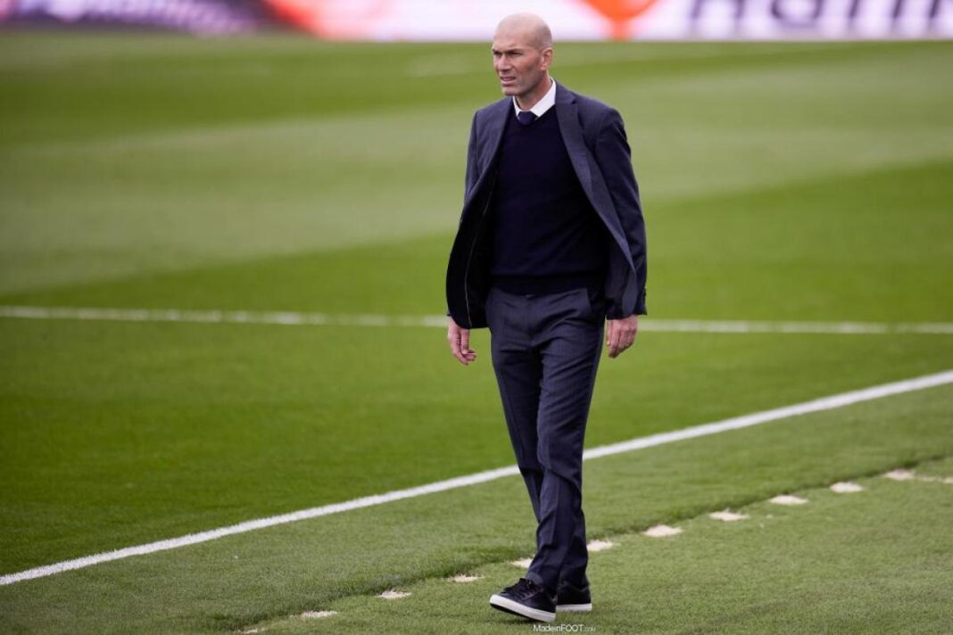 Zidane sur le terrain de football Zidane marchant sur le terrain de football en costume.