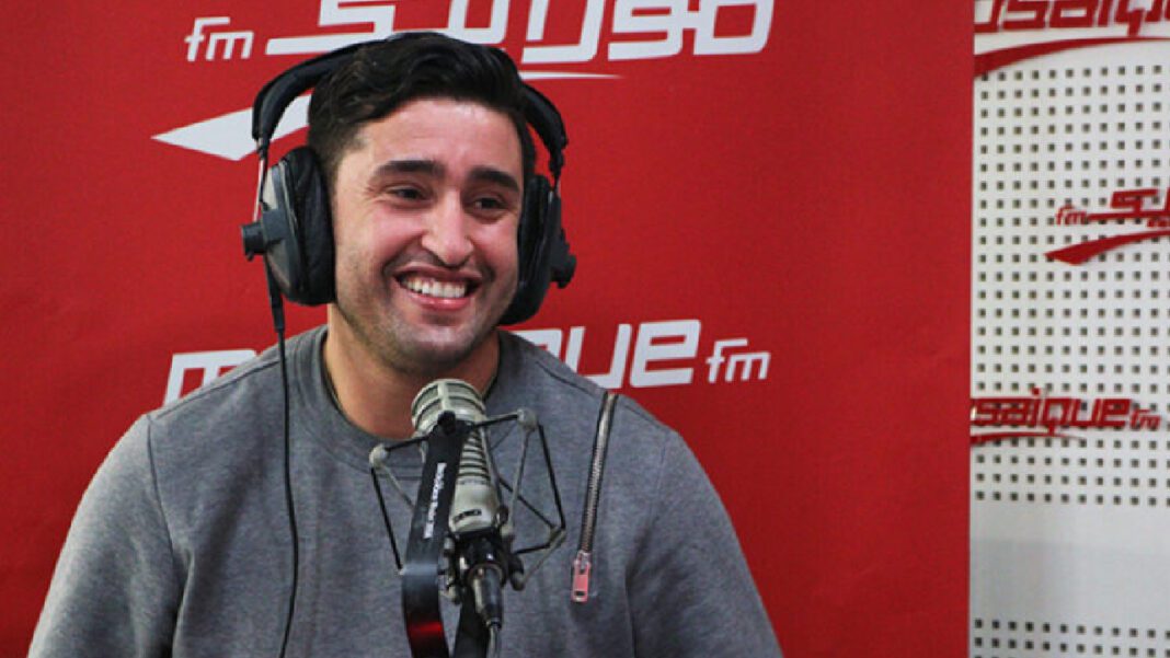 CHAN 2023 : le Tunisien Haggui félicite l’Algérie pour l’organisation Homme avec casque et micro dans un studio radio, sourire.
