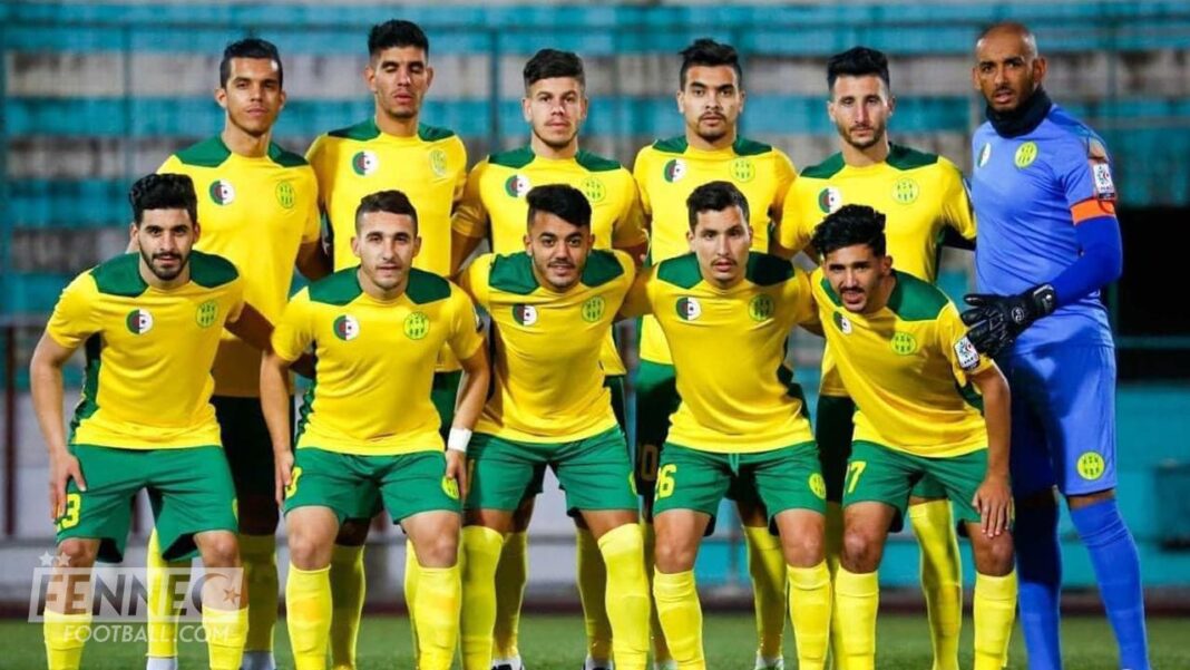 Groupe de joueurs de football algériens en tenue jaune et verte.