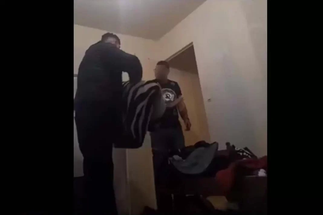 Homme en conflit avec un autre dans une pièce intérieure.