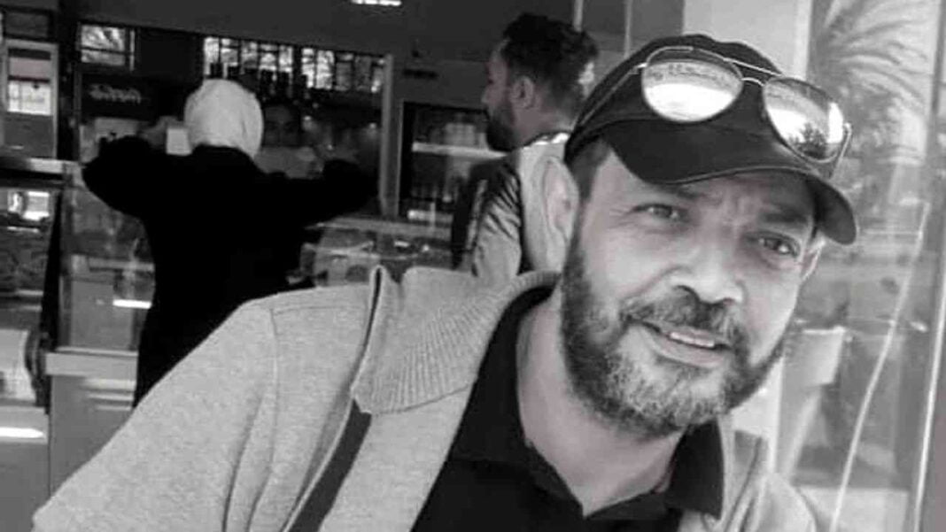 Décès de Nazim Kaidi en Algérie Homme souriant avec lunettes et barbe, en lieu public, en Algérie.