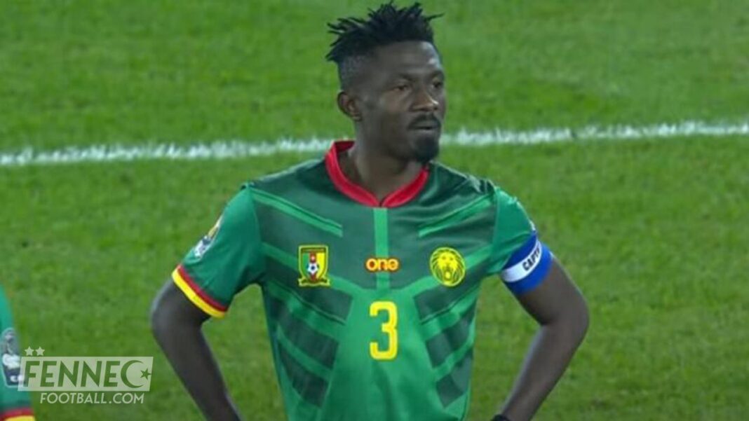 Joueur camerounais portant maillot vert avec numéro 3 et brassard bleu.