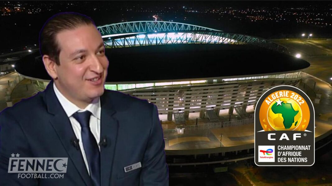 Jeune homme en costume devant un stade Jeune homme en costume souriant devant un stade illuminé la nuit.