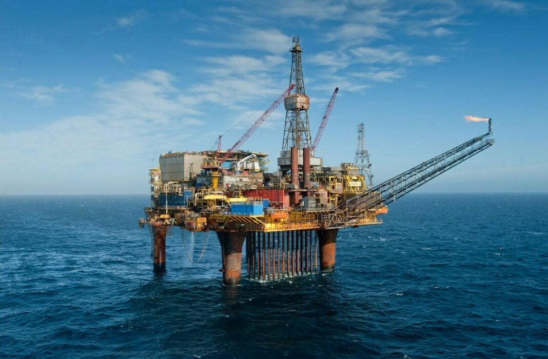 Plateforme pétrolière offshore en mer avec ciel bleu clair.