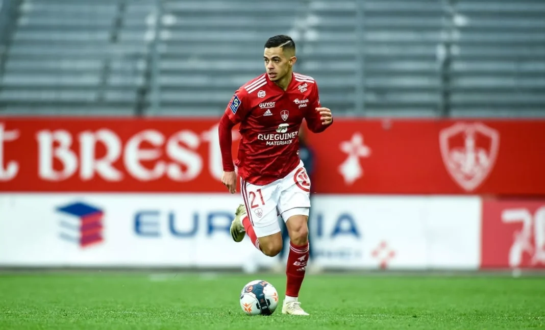Romain Faivre en action sur le terrain Romain Faivre lors d'un match de football, portant le maillot rouge.