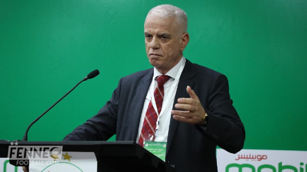 Coup de tonnerre ! Ces organisateurs de la CAN démissionnent pour cette incroyable raison Homme en costume lors d'une conférence avec fond vert.