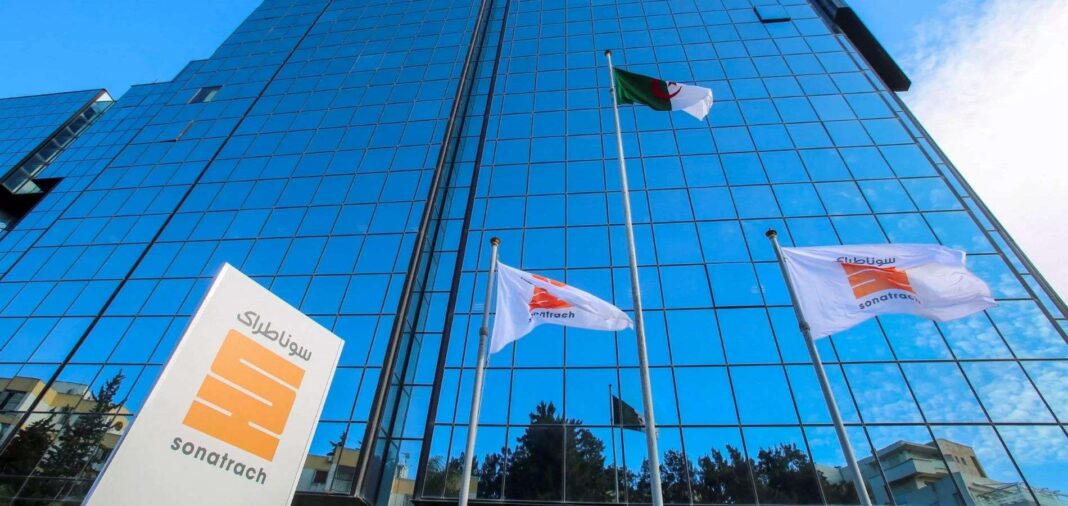 Bâtiment en verre avec drapeaux algérien et d'entreprise.