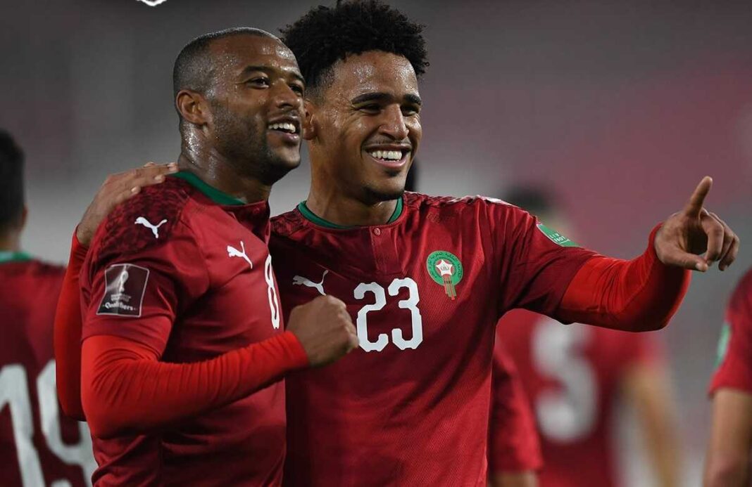 Deux joueurs marocains en tenue de football célébrant une victoire.
