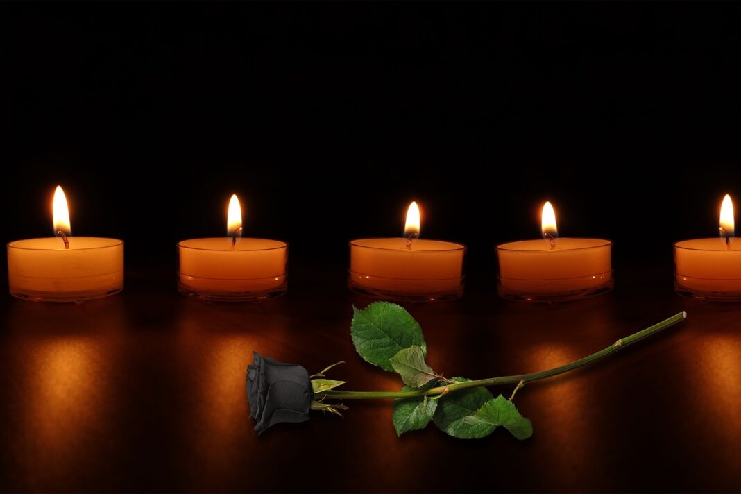 Cinq bougies allumées avec une rose noire en premier plan.