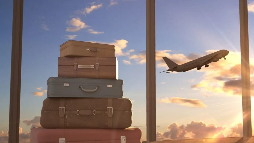 Voyage et départ en avion Valises empilées près d'une fenêtre avec avion en vol au coucher du soleil.