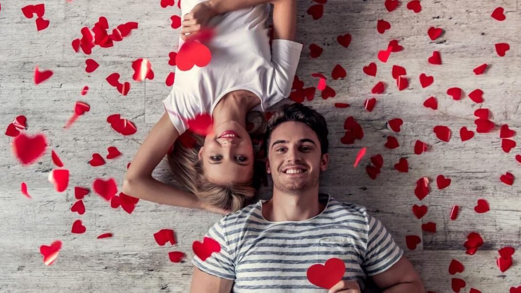 Célébration de la Saint-Valentin romantique Jeune couple heureux entouré de cœurs en papier rouge pour la Saint-Valentin.