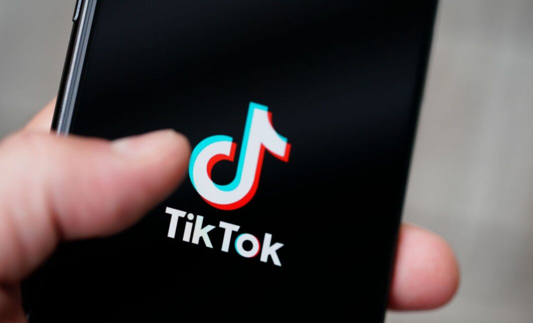 Logo TikTok affiché sur un smartphone tenu par une main.