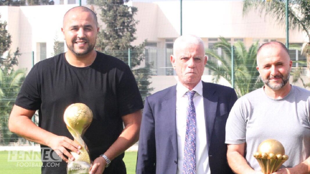 Madjid Bougherra offre un trophée à Djamel Belmadi lors d'une cérémonie sportive.