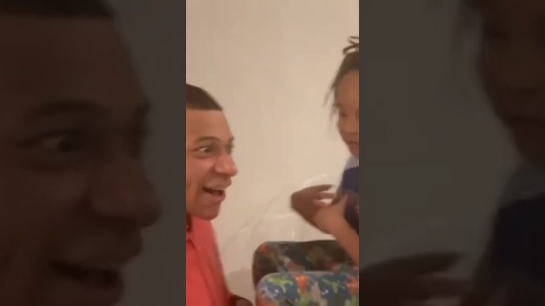 Kylian Mbappé souriant avec ses deux enfants dans une ambiance chaleureuse.