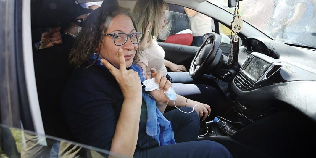 Amira Bouraoui dans une voiture Amira Bouraoui assise dans une voiture, portant des lunettes et un foulard bleu.