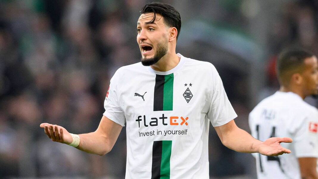 Ramy Bensebaini proteste sur le terrain lors d'un match de football.