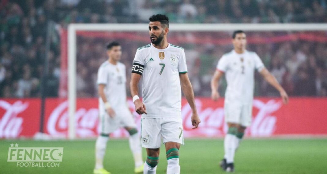 Riyad Mahrez lors d'un match de football Riyad Mahrez en action avec l'équipe d'Algérie sur le terrain.