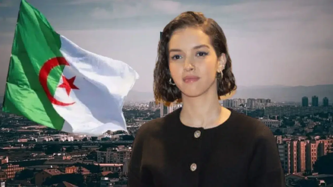 Lyna Khoudri devant le drapeau national algérien en arrière-plan.