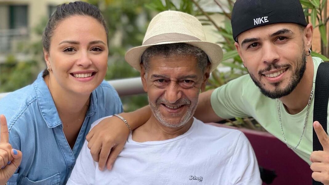 Algérie : Voici L’énorme confidence de Salah Aougrout qui laisse les internautes sans voix (Vidéo) Trois personnes souriantes, famille réunie en extérieur, ambiance chaleureuse.