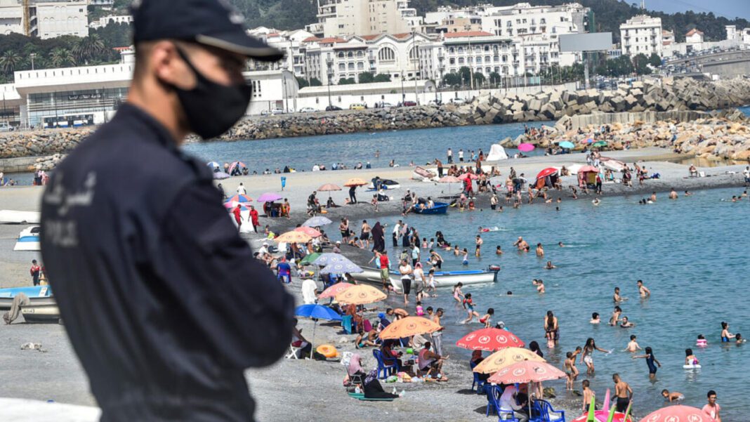 Plage bondée avec touristes et parasols colorés en Algérie.