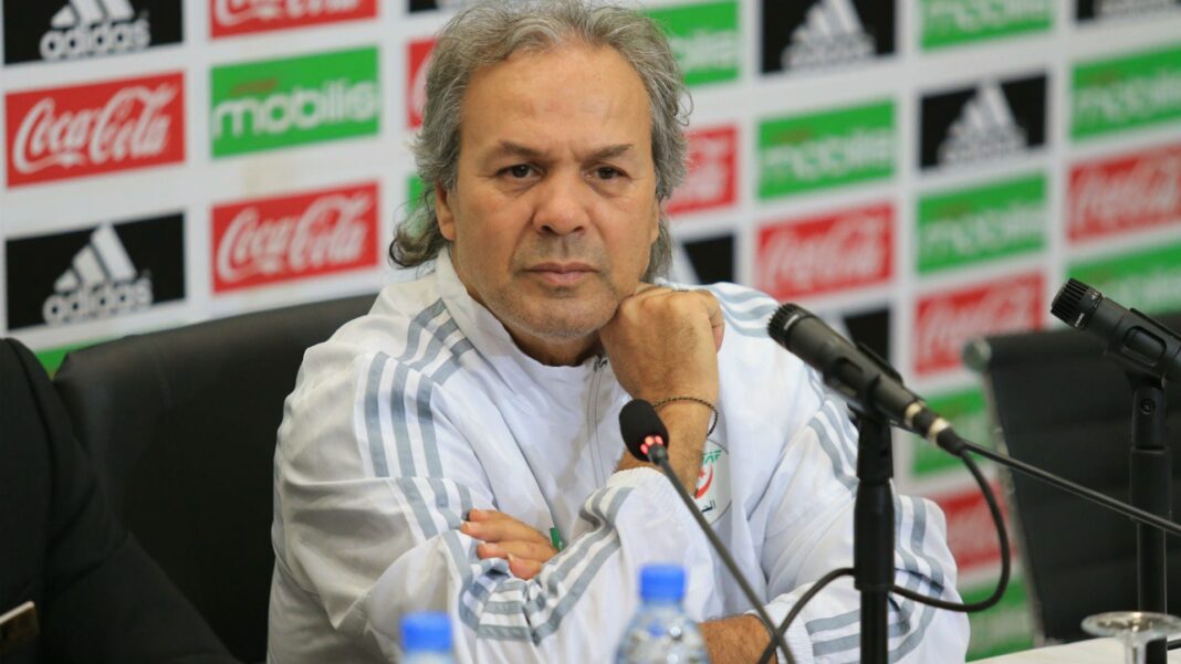 Algérie : Rabah Madjer secoué par une mauvaise nouvelle Rabah Madjer en conférence de presse, portant un maillot blanc et gris.