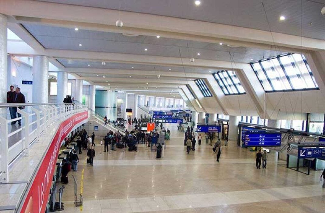 Espace d'attente moderne Vue intérieure de l'aéroport d'Alger avec passagers et panneaux d'information.