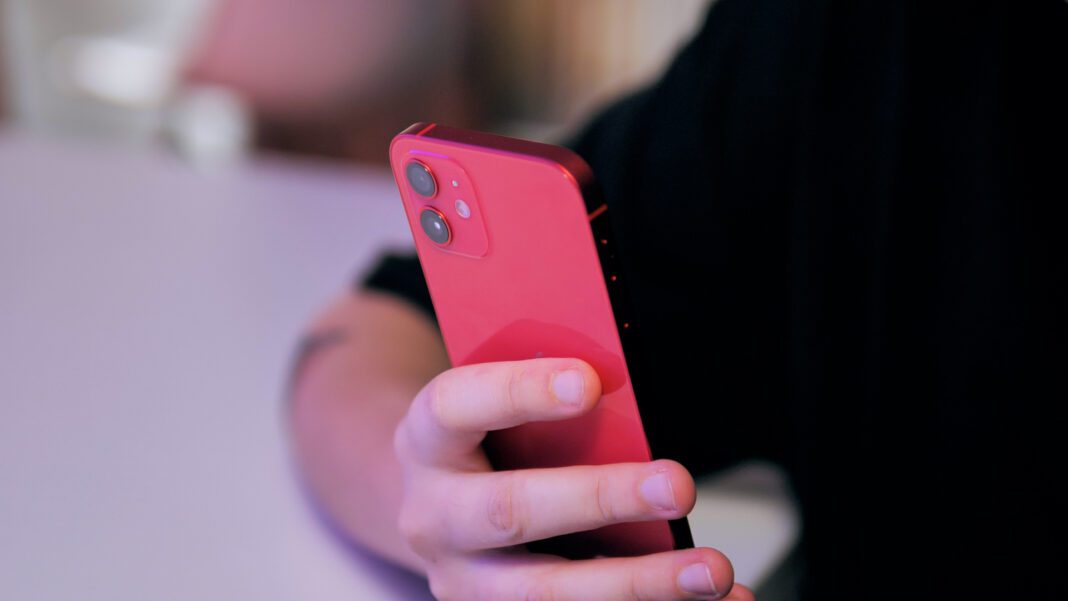 Incroyable ! Ce gamin s’est offert un iPhone 11 juste en mendiant. Enfant tenant un iPhone 11 rouge dans la main.