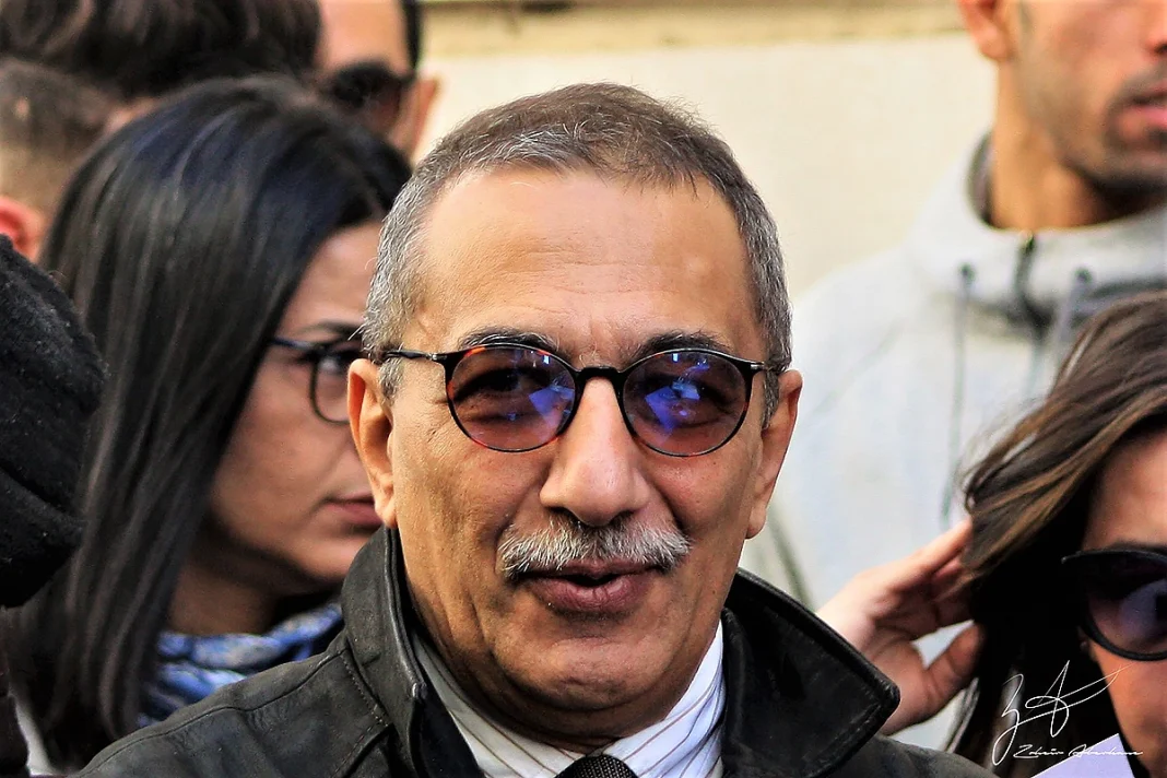 Verdict affaire Ihsane El Kadi : condamnation à 5 ans de prison dont 3 ans ferme Homme portant lunettes foncées lors d'une manifestation ou rassemblement.