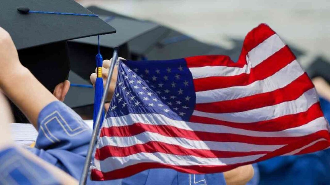 Aubaine ! Les États-Unis mettent à disposition des algériens des bourses d’études. Découvrez. Étudiants en graduation tenant un drapeau américain.