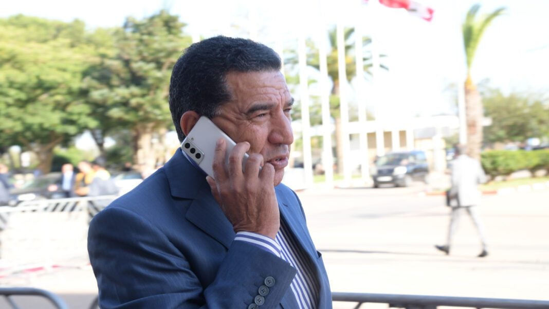 Maroc : l’ancien Ministre Mohamed Moubdi déposé en prison pour corruption et abus de biens sociaux Homme en costume parlant au téléphone dans un espace extérieur.